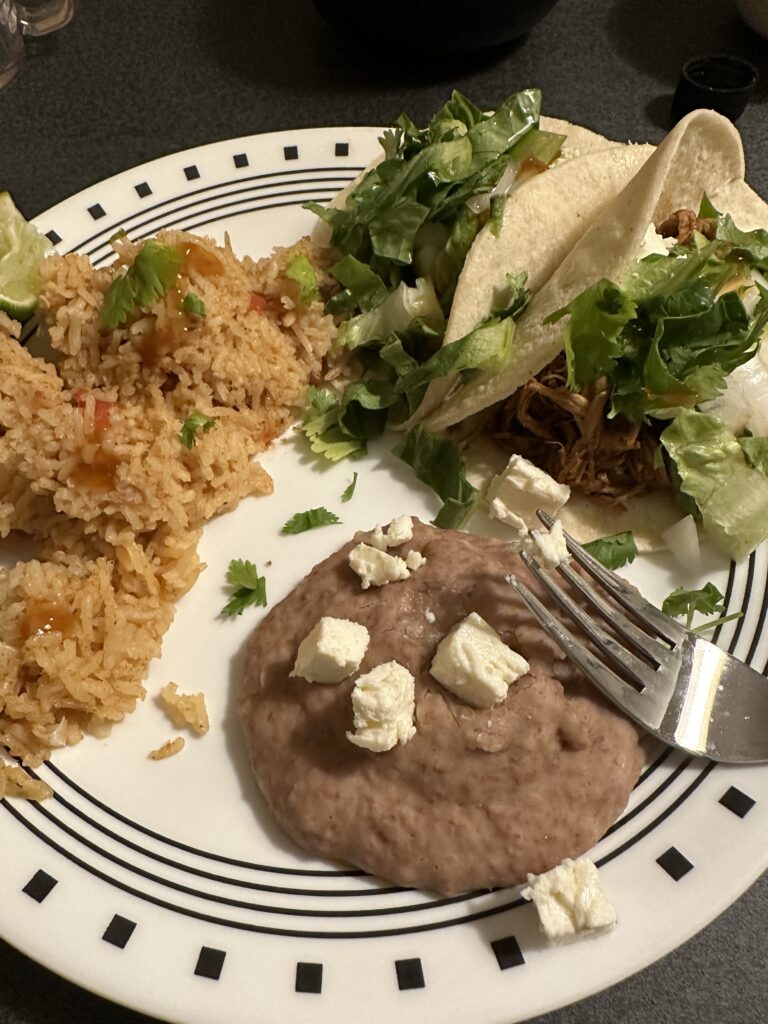 Refried beans with chunks of feta cheese, a pile of Mexican rice, and a corn tortilla loaded with pork, avocado, lettuce, onions
, cilantro, and the flavorful pepper hot sauce. 
