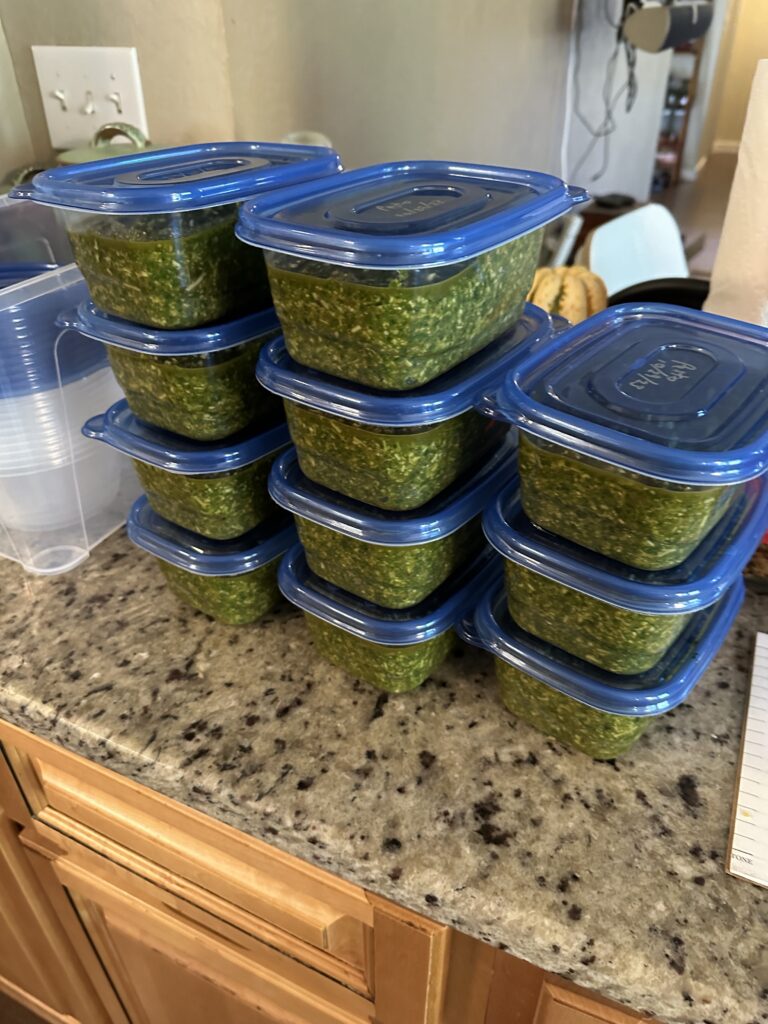 Three stacks of several plastic clear containers of pesto, totalling 11 containers. 