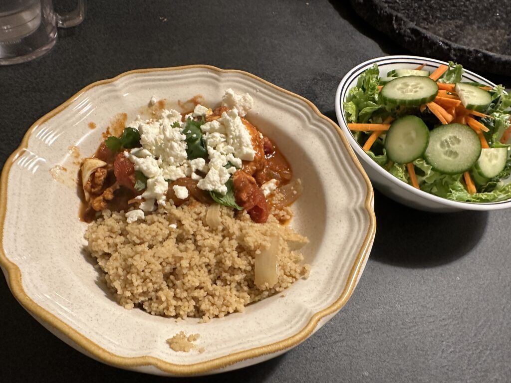 Shakshuka and couscous next to a bowl of salad